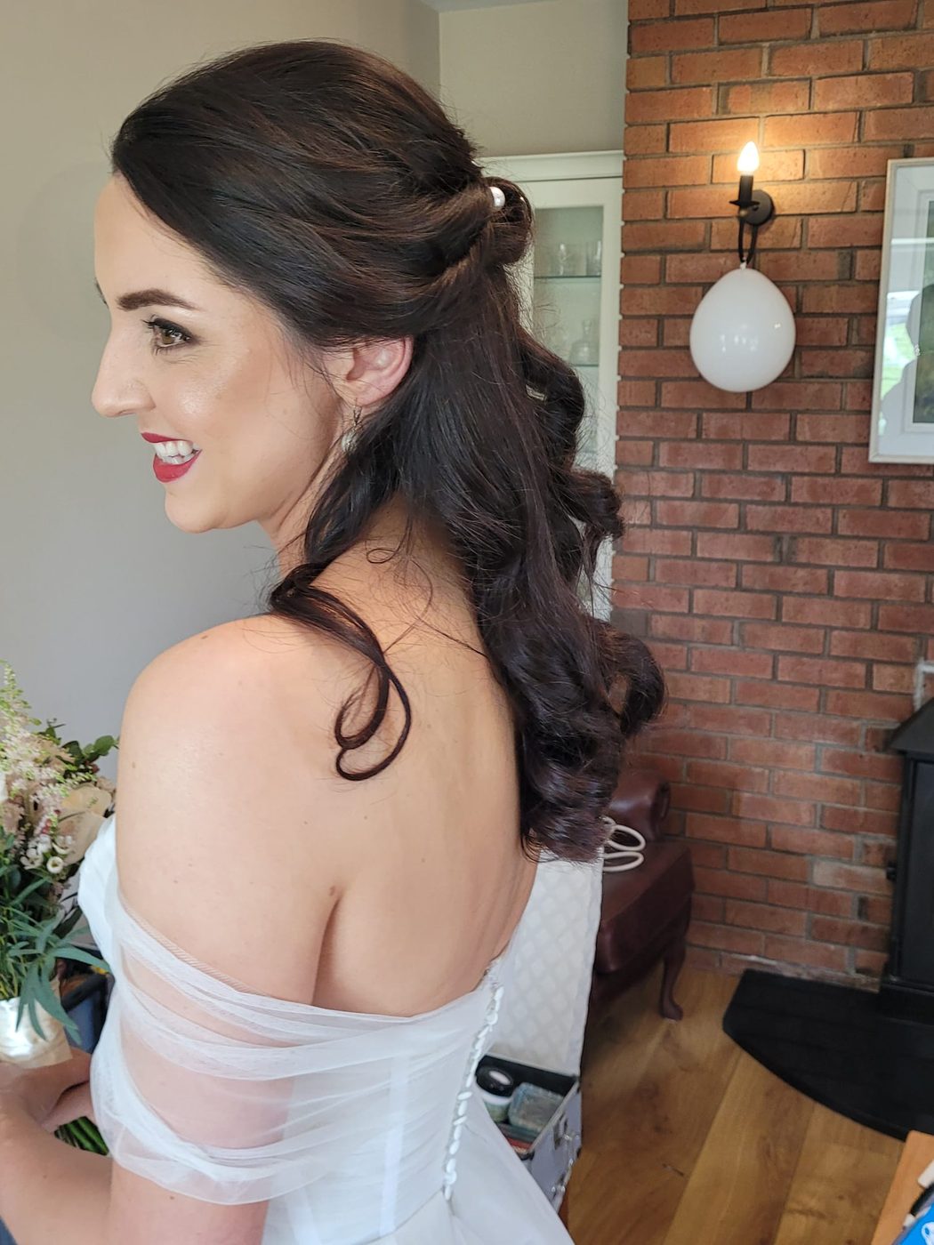 A dark half-up style with soft curls, styled at INCH Hair Design