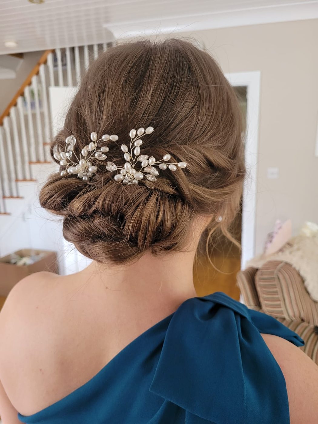 Bridal low bun dressed with a pearl hairpiece at INCH Hair Design