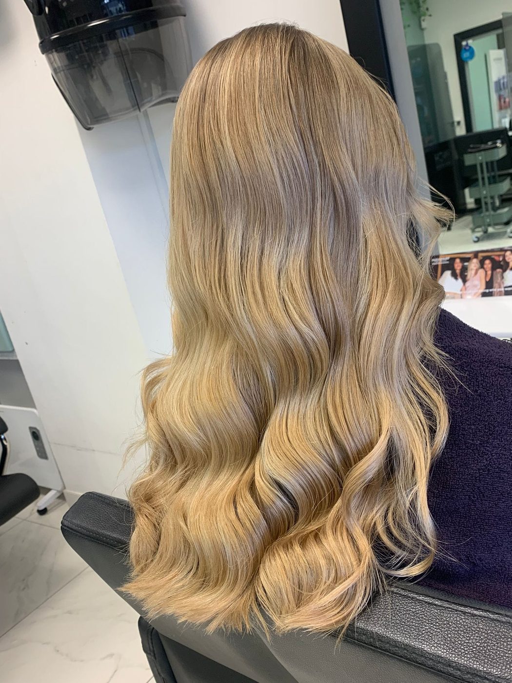 Long blonde balayage with a glossy wavy blow-dry at INCH Hair Design