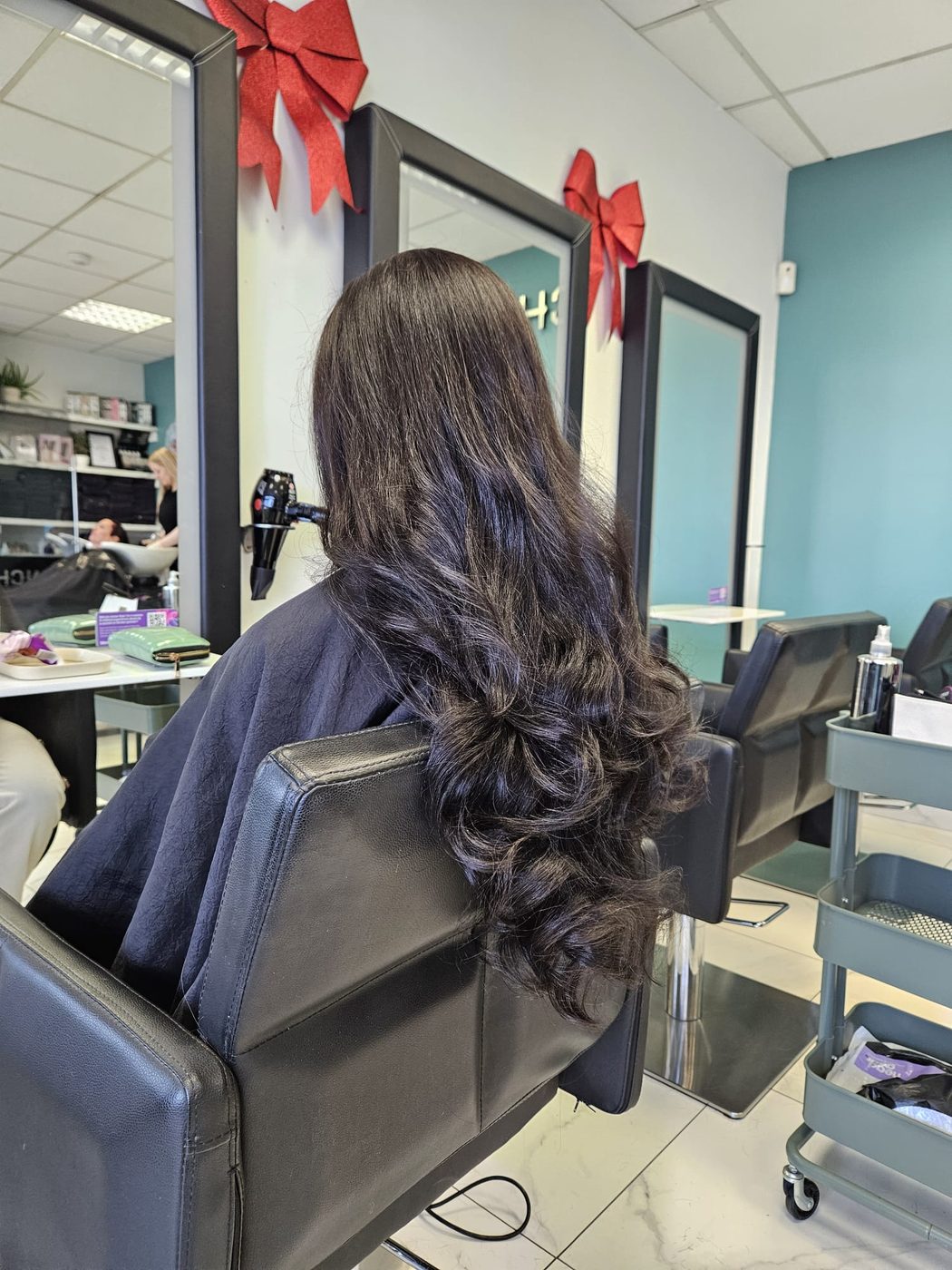 Rich, glossy dark colour with long curls at INCH Hair Design
