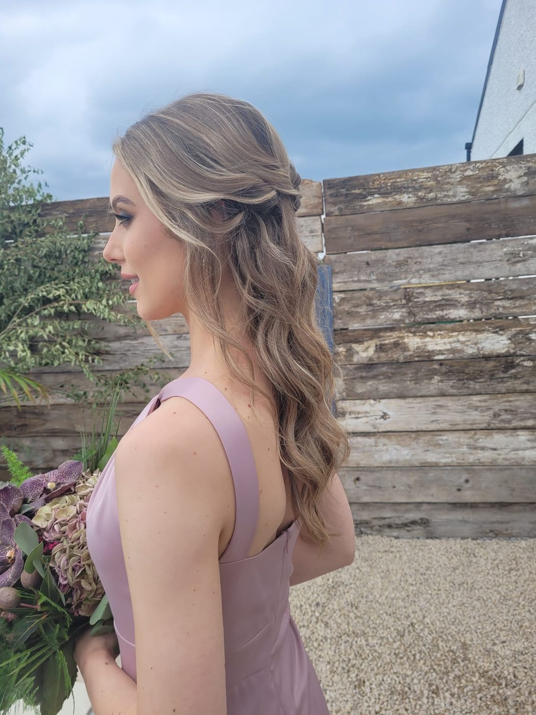 A half-up blonde style with soft waves, styled at INCH Hair Design